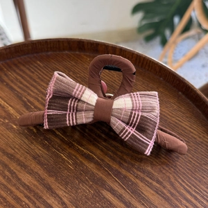 Pince à cheveux à nœud à carreaux roses sur plateau en bois, style français minimaliste