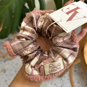 Détail d'un chouchou en polaire rose avec tissu à carreaux et nœud en satin