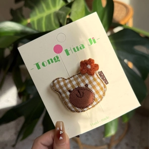 Handmade yellow plaid teddy bear hair clip with orange knit flower on card