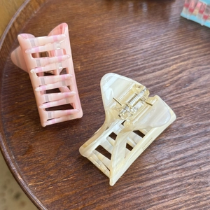 Detailed view of handmade pink striped and marble cream acetate hair claw clips on wood