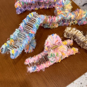 Detail of colorful plush-wrapped hair claw clips on a rustic wooden table background