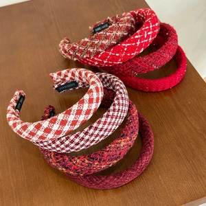 Detail showing red plaid and tweed headbands with handmade labels on wooden surface