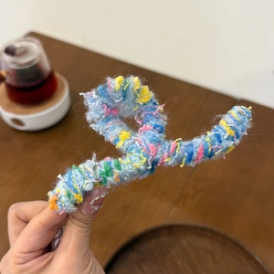 Colorful plush woven hair claw clip with warm knit texture for cozy winter styling
