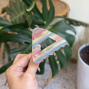 Close-up of a striped triangle hair claw clip with pearlescent pink and blue patterns
