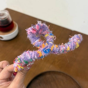 Detail of a purple twisted yarn-wrapped hair claw clip with colorful thread texture