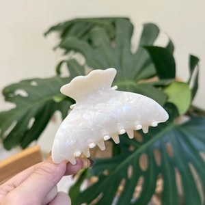 Elegant cream white acetate hair claw clip with shell luster texture held in hand