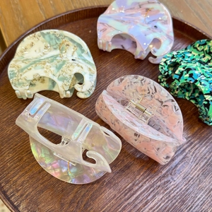 Selection of acetate shark hair claws in marble and floral patterns on a wooden tray