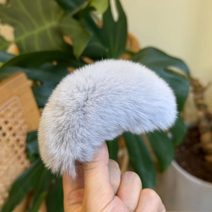 Macro detail van een pluche grijze faux fur haarklem met zachte textuur gehouden in de hand