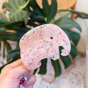 Handmade pink elephant hair claw clip with marble texture shown against green leaves