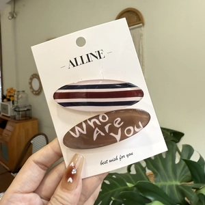 Macro detail of resin hair clips featuring horizontal stripes and artistic letter patterns
