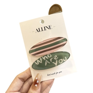 Pastel striped and green lettered hair clip set on a white brand display card