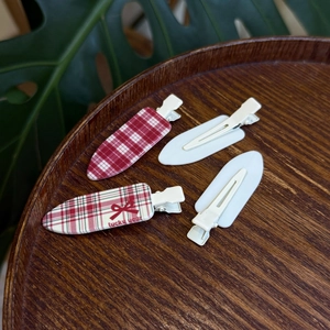 Set of four red and white plaid hair clips with lucky year bow on a wooden tray