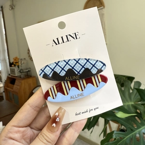 Set of two vintage checkered hair clips with wavy patterns on a brand display card