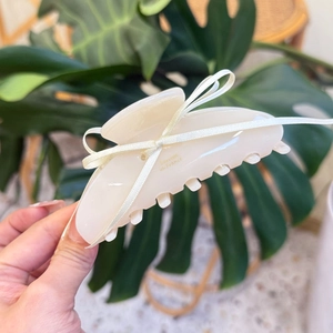 Elegant cream acetate shark hair claw clip with white ribbon and golden lettering