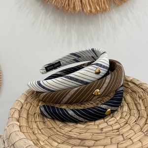 Detail view of striped padded headbands featuring golden heart charms and handmade labels