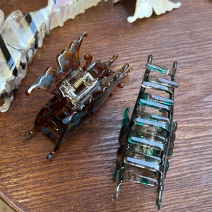 Gros plan sur pince à cheveux papillon en acétate et clip rectangle vert sur bois