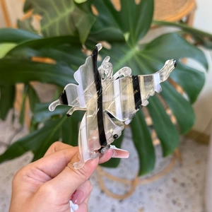 Détail macro d'une pince à cheveux papillon en acétate à rayures noires et blanches et dorure