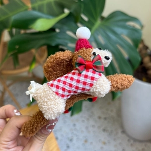 Détail d'une pince à cheveux caniche de Noël en peluche avec gilet à carreaux rouges
