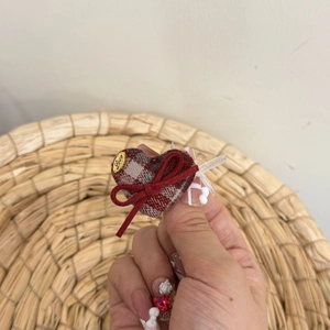 Detail of red plaid heart hair accessory with a bow and gold Love metal tag