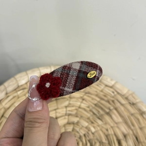 Close-up of red plaid fabric hair clip with a crochet flower and Love metal tag