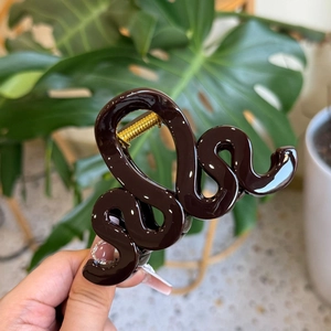 Détail de la pince à cheveux ondulée marron foncé avec ressort doré et feuilles