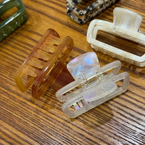 Assorted acetate hair claws in amber, cream, and tortoiseshell on a wooden surface