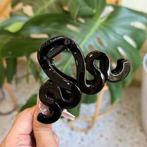 Détail de la pince à cheveux noire en forme de serpent avec finition brillante sur feuilles