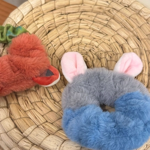 Detail of plush cartoon bunny ears and carrot hair scrunchies in a woven basket