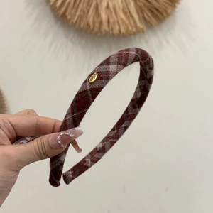 Macro detail of red plaid headband featuring a gold oval Love engraved metal plate