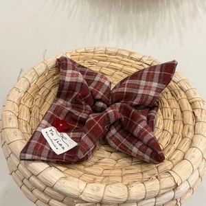 Detailed view of the red plaid bow hair accessory with handmade label and crochet flower