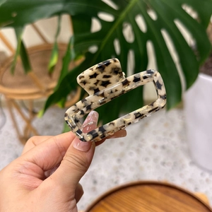 Close-up of tortoise shell pattern acetate hair claw clip with golden branding text