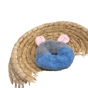 Cute plush grey and blue hair scrunchie with pink ears on a round woven mat