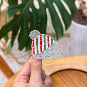 Gros plan d'une pince à cheveux bonnet de Noël avec rayures rouges, vertes et paillettes