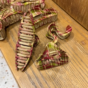 Detail of assorted hair claw clips with red and green plaid patterns on a wooden surface