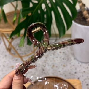 Close-up of a large checkered hair claw clip with dark green and brown tartan patterns