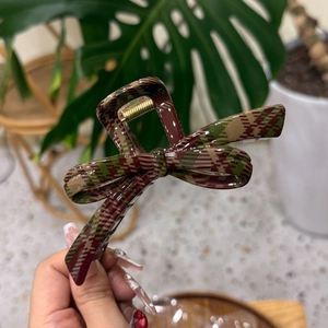 Close-up of a large checkered hair claw clip with green and brown vintage patterns