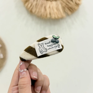 Detalle de horquilla de punto con rayas marrones, decorado de bayas y etiqueta de un oso