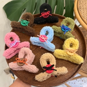 Close-up of plush teddy fleece claw clips with colorful button bow accents in various colors