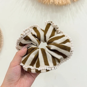 Coletero de punto a rayas marrones y crema con borde festoneado en la mano