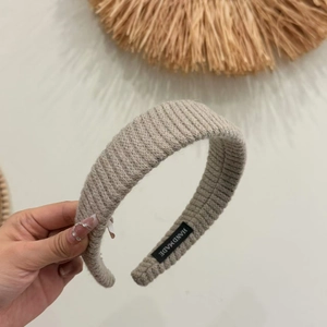 Detail showing ribbed knit texture and handmade label on wide khaki headband