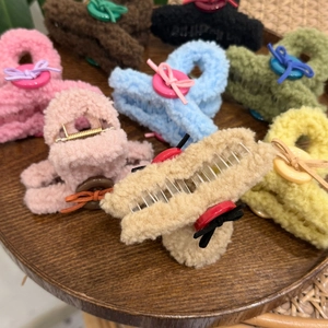 Close-up of plush teddy fleece claw clips with decorative buttons and ribbon bows