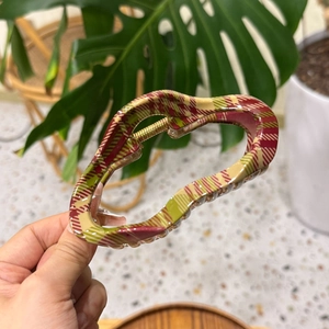 Close-up of a large hair claw clip with red and green plaid pattern and gold spring