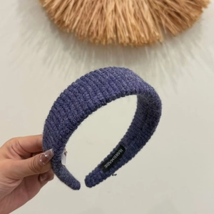 Detail of purple ribbed knit headband with handmade label showing high-quality texture