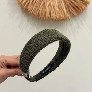 Dark green knitted wide headband with ribbed texture and handmade label on soft fabric