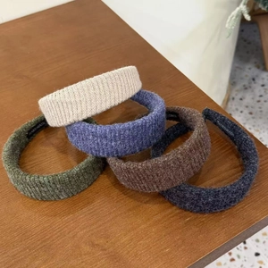 Detail of five colored waffle-knit wide headbands displayed on a wooden surface