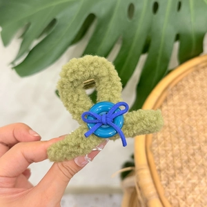 Grass green plush claw clip with a blue button and bow accent for hair styling