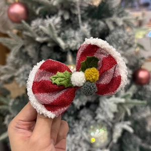 Detail of a Christmas bow hair clip with red sequins, white faux fur trim and pom-poms