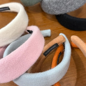 Detailed close-up of handmade wide wool headbands showing fabric texture and woven labels