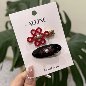 Dettaglio di fermagli per capelli con nodo cinese rosso e fiori neri con perle