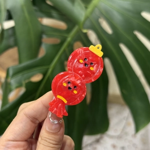 Dettaglio di un fermaglio per capelli a forma di lanterna rossa festiva con faccina emoji